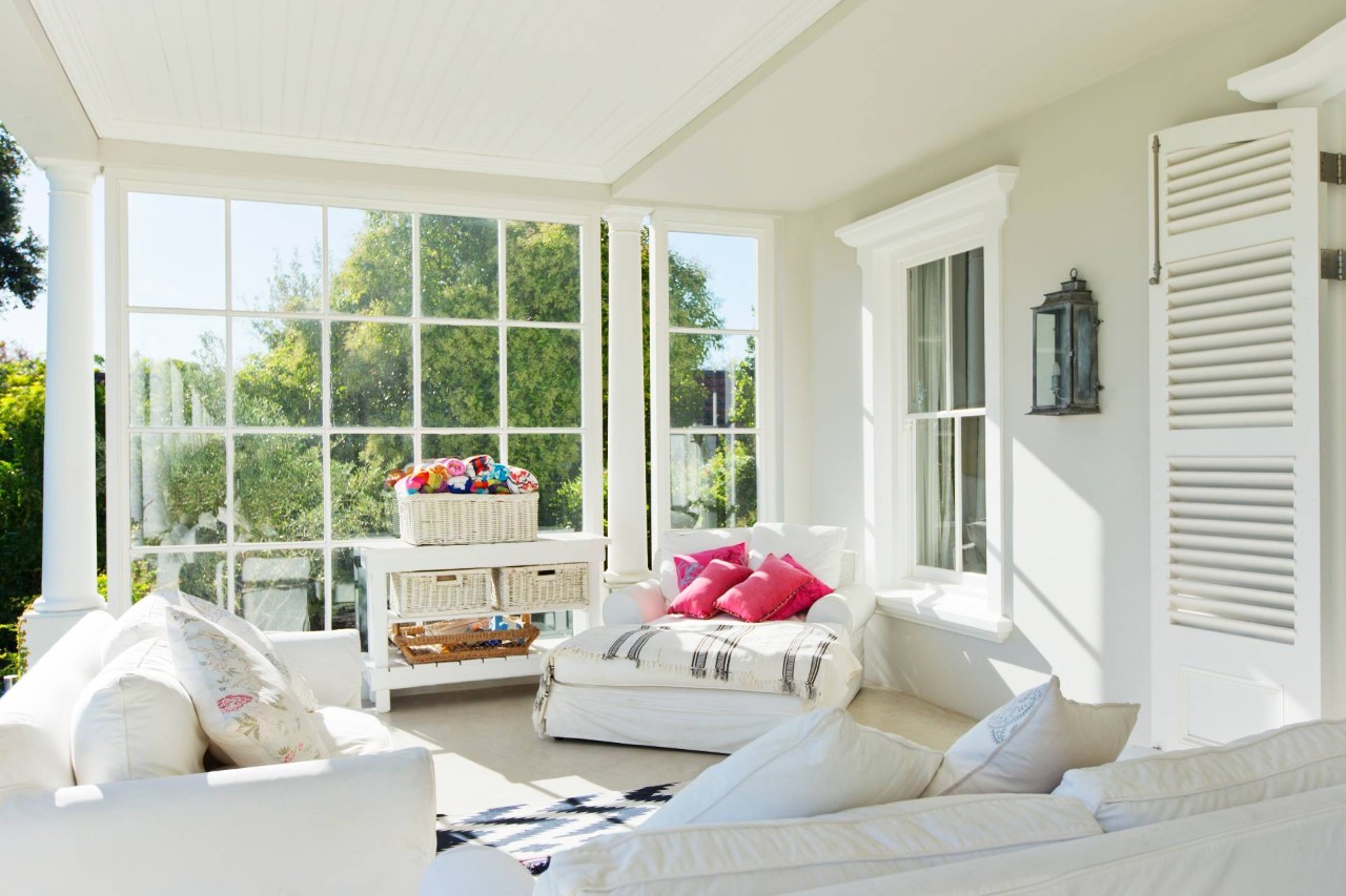 An enclosed sunroom with white furniture and colorful accents items at Blind Ambitions near Tulsa, OK